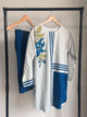 White dress with blue accents and floral embroidery on a hanger against a neutral background